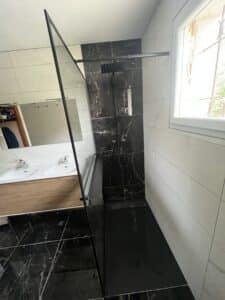 Salle de bain moderne avec douche à l'italienne marbre noir, parois vitrées, double vasque bois et carrelage blanc marbré. Sol marbre noir.